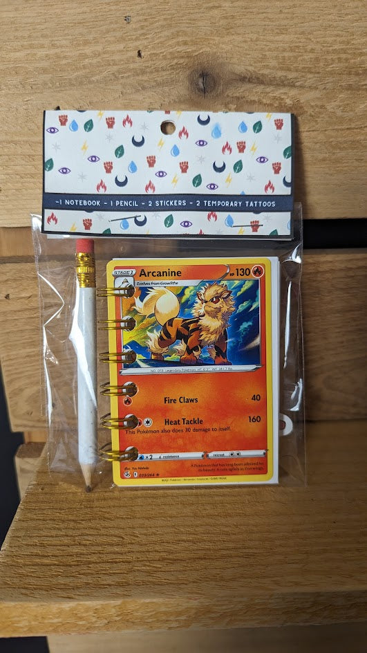 Example image of Pokémon card notebook packaged with pencil two random temporary tattoos, and two random stickers.. 