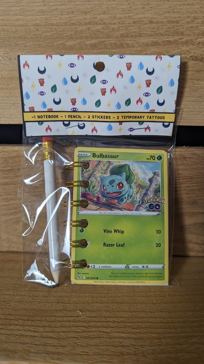 Pokémon card notebooks are packaged with a pencil, two random stickers, and two random temporary tattoos.