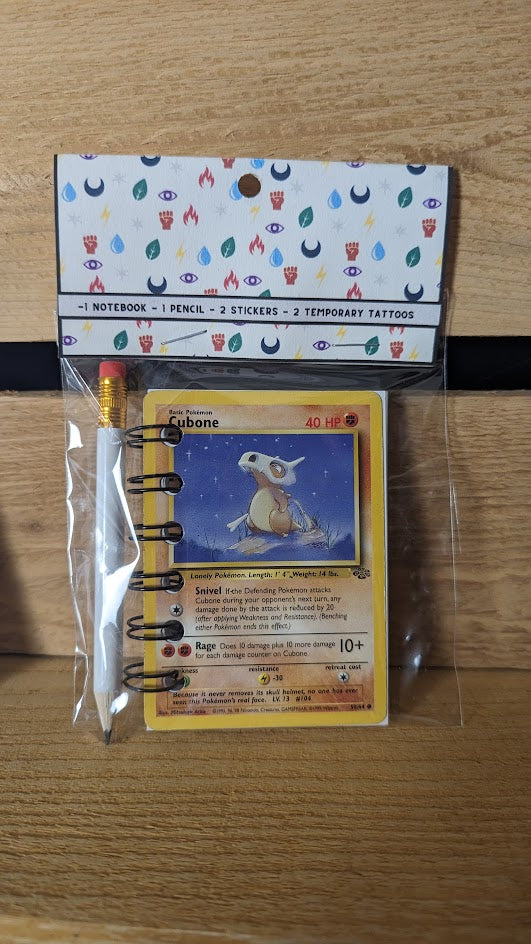 Pokémon card notebooks are packaged with a pencil, two random stickers, and two random temporary tattoos.