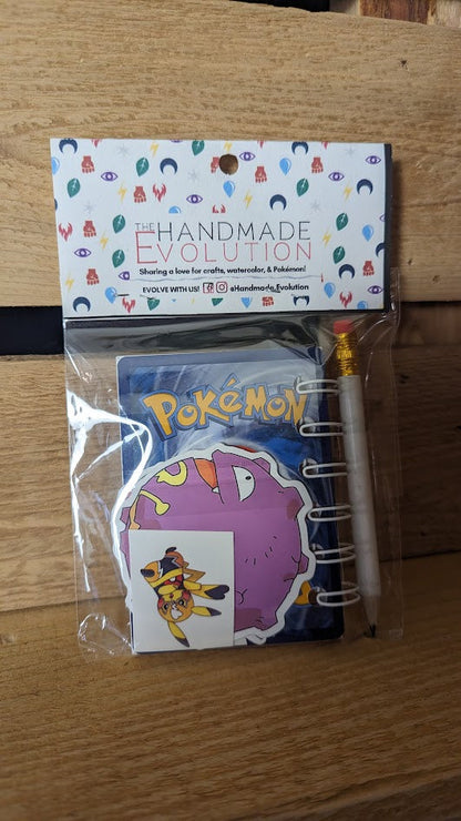 Eample of the back of the packaged Pokémon card notebook. Notebooks are packaged with two random stickers, a pencil, and two random temporary tattoos. 