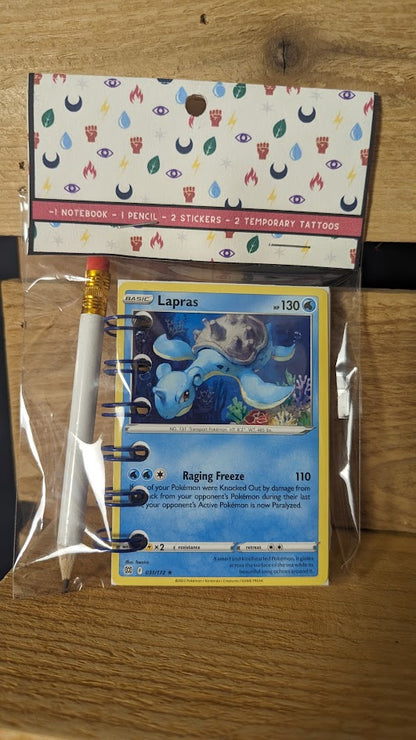 Pokémon card notebooks are packaged with a pencil, two random stickers, and two random temporary tattoos.