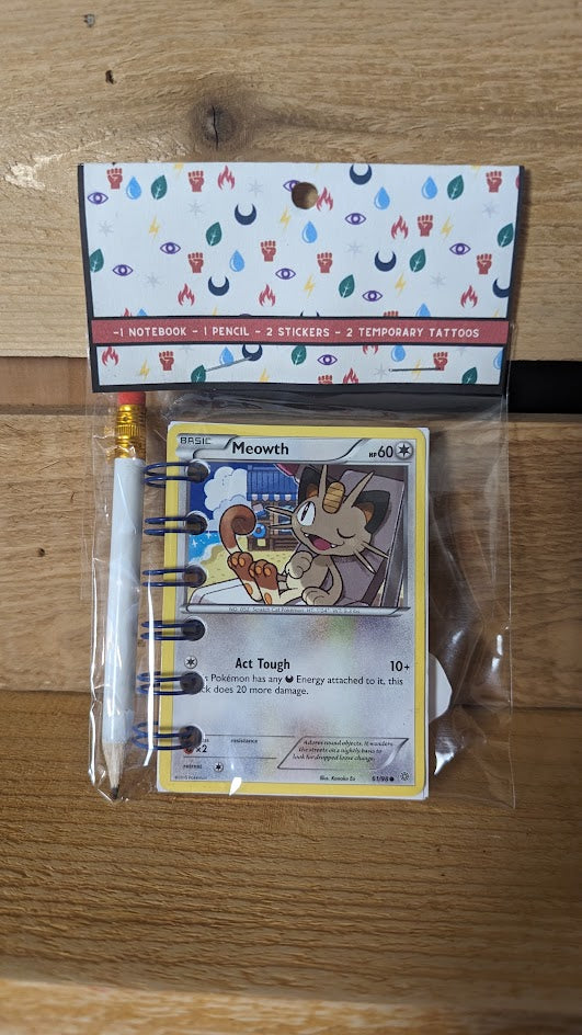 Pokémon card notebooks are packaged with a pencil, two random stickers, and two random temporary tattoos.