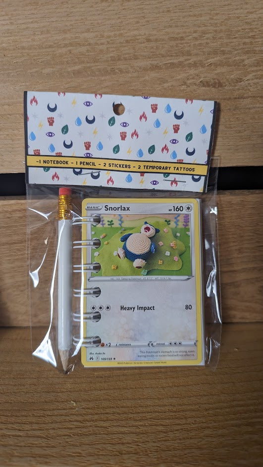 Pokémon card notebooks are packaged with a pencil, two random stickers, and two random temporary tattoos.