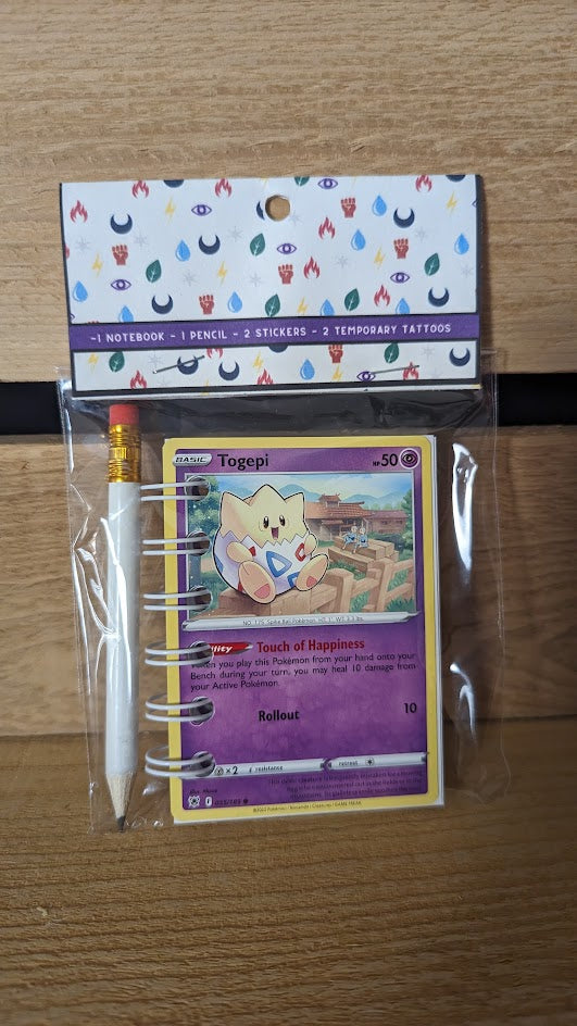 Pokémon card notebooks are packaged with a pencil, two random stickers, and two random temporary tattoos.