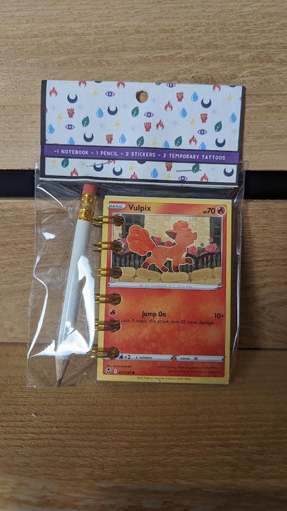 Pokémon card notebooks are packaged with a pencil, two random stickers, and two random temporary tattoos.