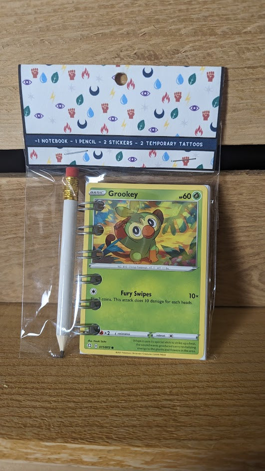 Pokémon card notebooks are packaged with a pencil, two random stickers, and two random temporary tattoos.