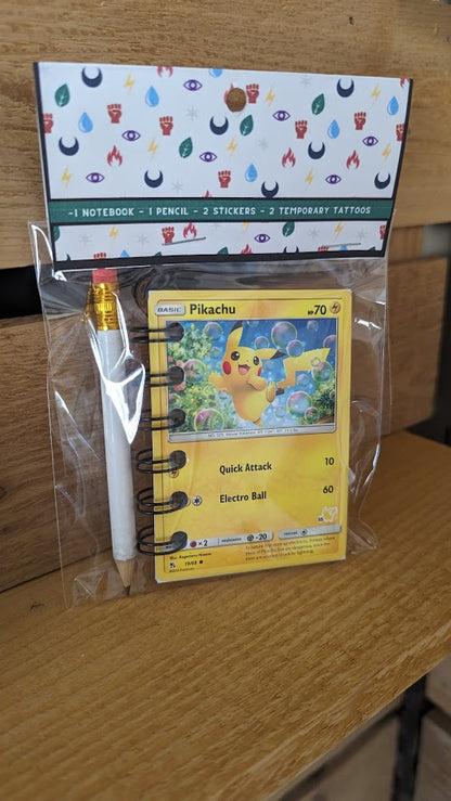 Pokémon card notebooks are packaged with a pencil, two random stickers, and two random temporary tattoos.