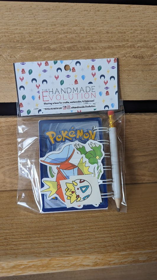 Pokémon card notebooks are packaged with a pencil, two random stickers, and two random temporary tattoos.