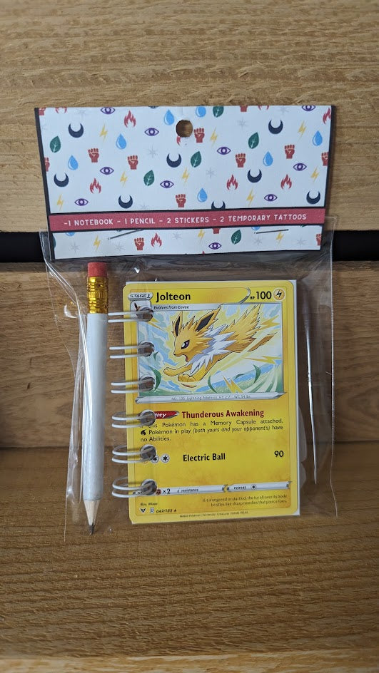 Pokémon card notebooks are packaged with a pencil, two random stickers, and two random temporary tattoos.