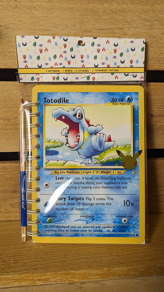 Pokémon card notebooks are packaged with a pencil, two random stickers, and two random temporary tattoos.